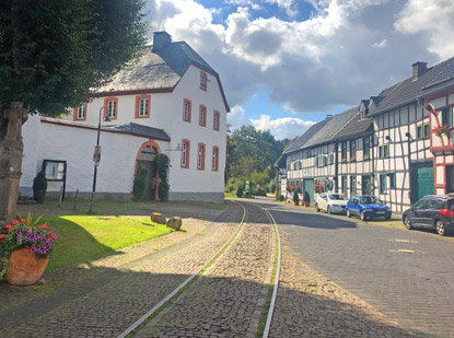 Eifelsteig Etappe 5: Bahngleise führen über den Dorfplatz von Olef