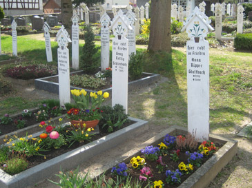 Nibelungensteig: Calvinisten ist das Schmücken der Gräber untersagt. Deshalb sind auf dem Friedhof in Schlierbach im Odenwald nur weiße bemalte Holzlatten mit einem Blumentopfbild anzutreffen (Stickelbretter)